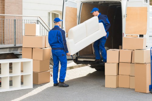 A local removals team carrying furniture through a residential entrance in Kentish Town