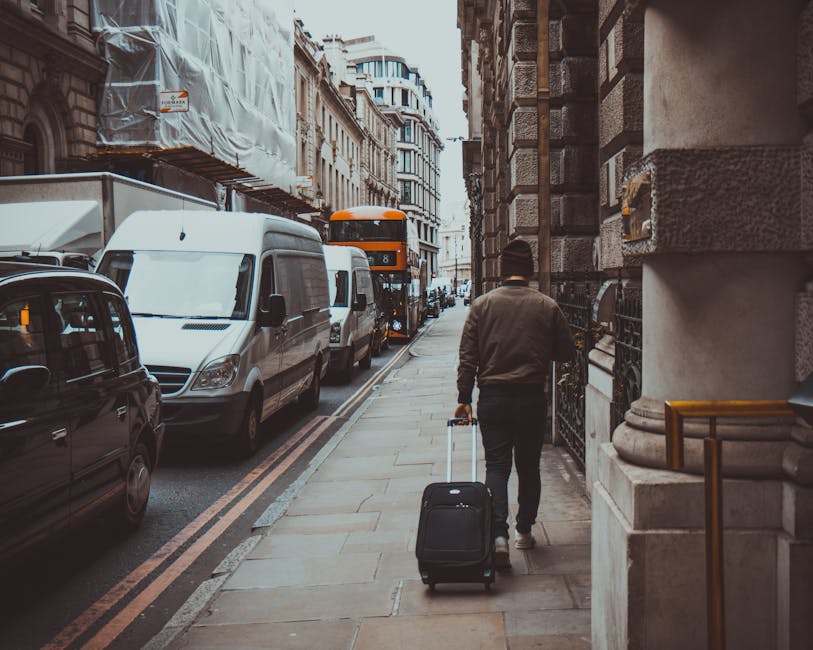 A white moving van branded with the company's logo and the words 'Moving Company Local & Long Distance' is parked on the street in front of a two-storey residential building with a combination of whit